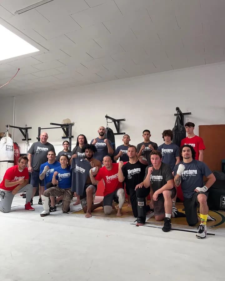 A large group of members and coaches gathered together on the gym floor