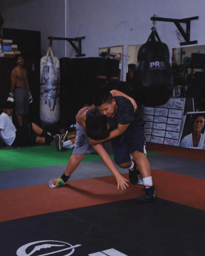Two members wrestling beside the heavy bags